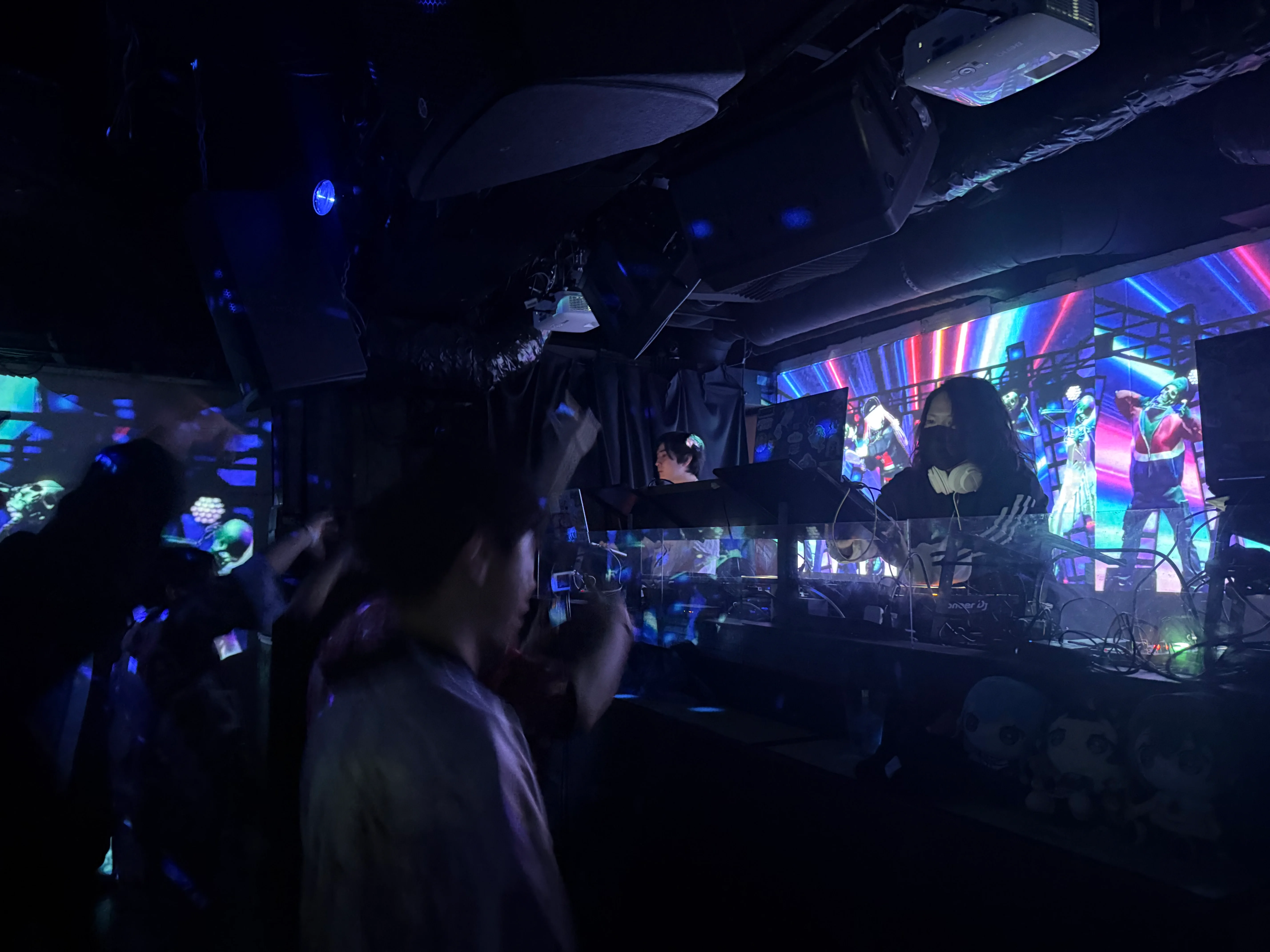 DJ performing at a live club night with LED visuals and crowd