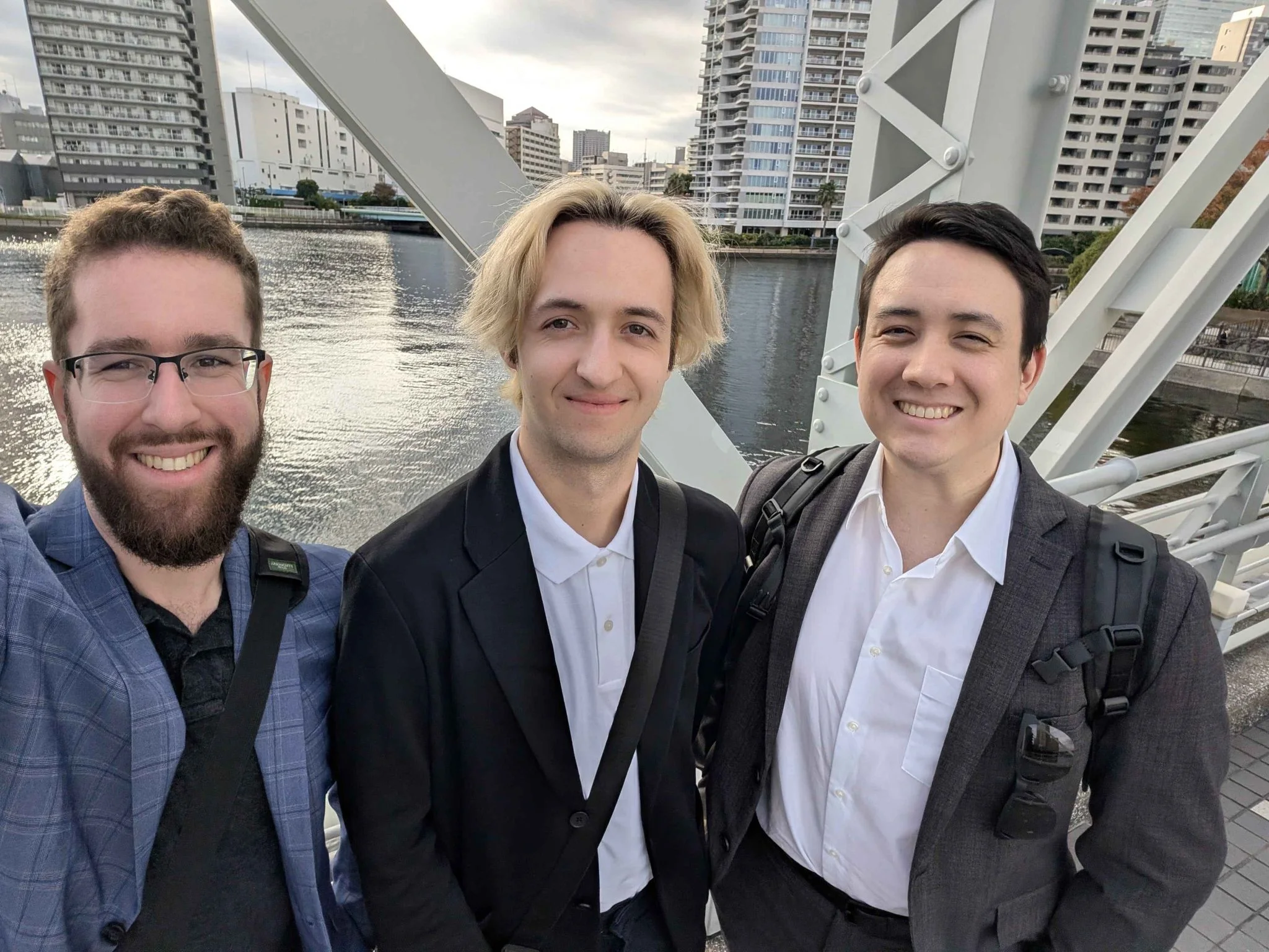 Three Veizo partners standing together on a bridge with a city skyline and water behind them